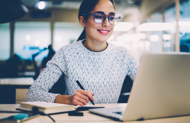 junge Frau arbeitet am Laptop und lächelt dabei