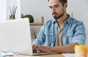 Junger Mann arbeitet am Laptop