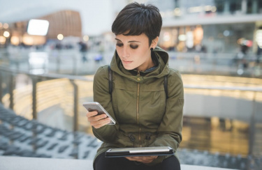 junge Frau schaut auf Smartphone und Tablet
