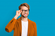 Mann fasst sich an seine Brille und schaut lächelnd zur Seite