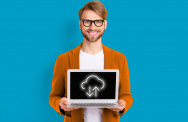 Mann mit Brille hält freundlich einen Laptop mit Cloudwolke in der Hand