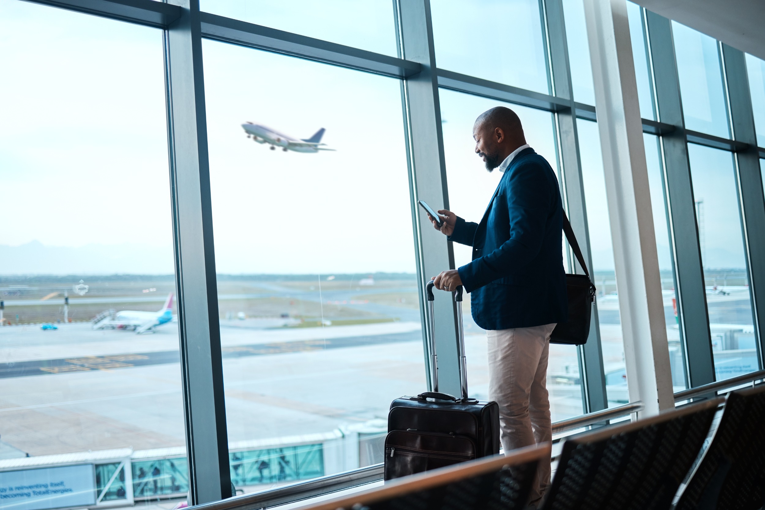 Ein Mann steht mit einem Koffer am Fenster im Flughafen