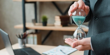 Mann hält eine Sanduhr