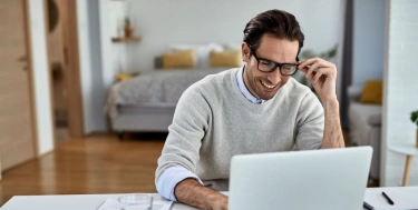 Zufriedener Freelancer arbeitet von zu Hause aus am Computer