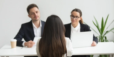 Zwei Arbeitskollegen führen ein Vorstellungsgespräch mit einer Bewerberin