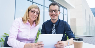 mann und frau sitzen am tisch mit tablet in der hand