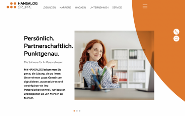Junge Geschäftsfrau mit einem Lächeln, die an ihrem Schreibtisch im Büro sitzt und die Kamera betrachtet