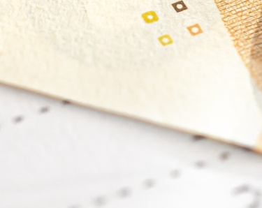 Nahaufnahme von Taschenrechner, Geldscheinen und Bleistift vor verschwommenem Hintergrund