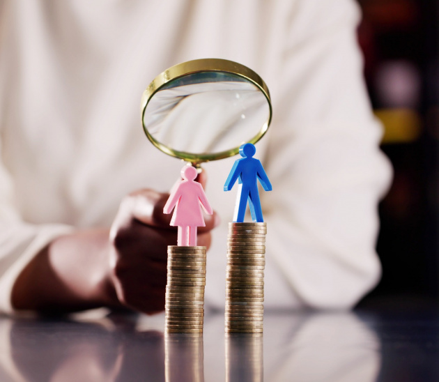 Eine Frau- und eine Mannfigur stehen auf ungleich hohen Geldstapeln, im Hintergrund wird das Ungleichgewicht durch eine Lupe hervorgehoben.